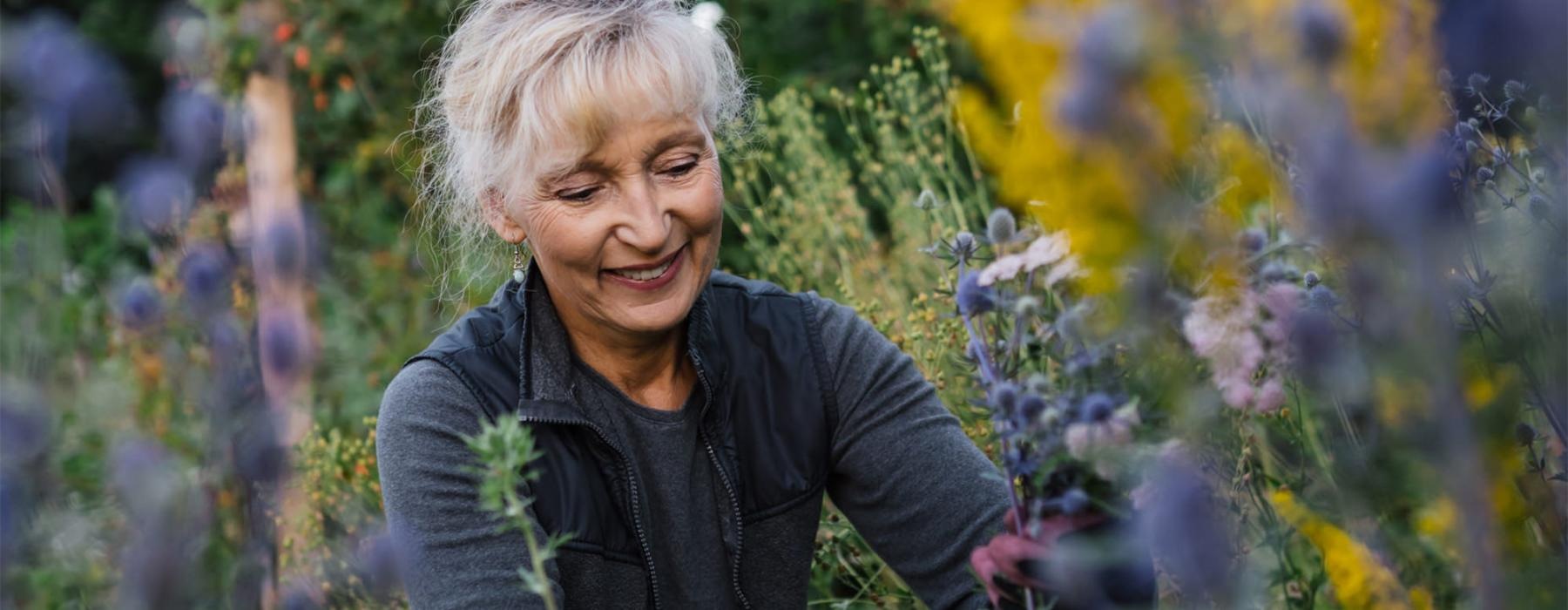 a woman kneeling in a field of plants