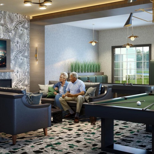 a group of people sitting on a couch in a room with a large screen and a pool table