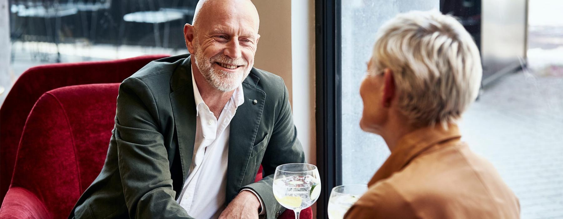 a man and a woman sitting at a table with cocktails